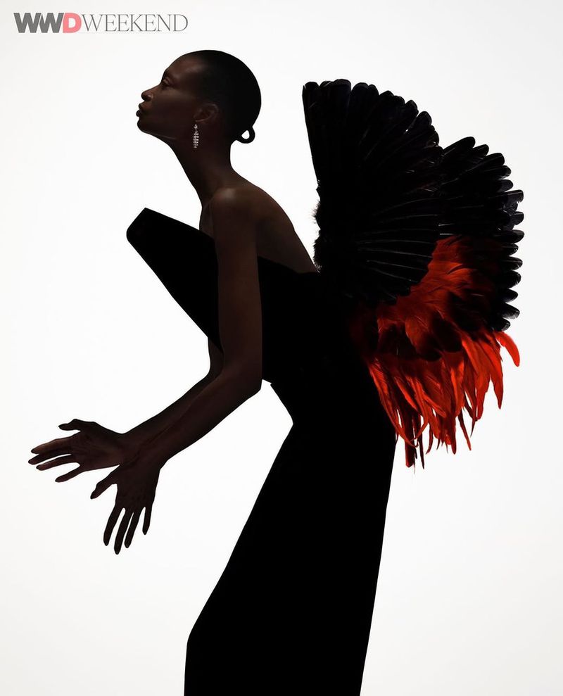 Fashion model poses in black strapless gown with red and black feather detail in a studio shot, editorial fashion for WWD Weekend.