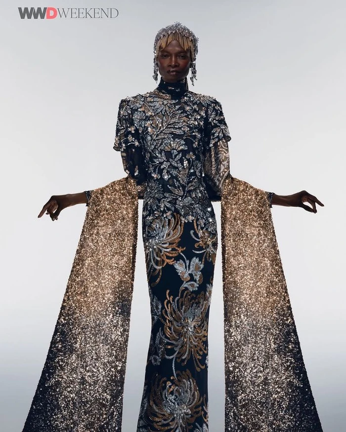 Model Debra Shaw wearing a heavily embellished gown with cascading glitter sleeves and a matching headpiece for WWD