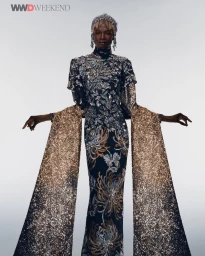 Model Debra Shaw wearing a heavily embellished gown with cascading glitter sleeves and a matching headpiece for WWD