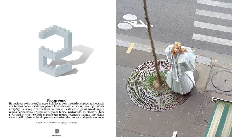 Fashion editorial shot from above shows a model in a voluminous dress standing near a tree on a city sidewalk. A toy brick is nearby.