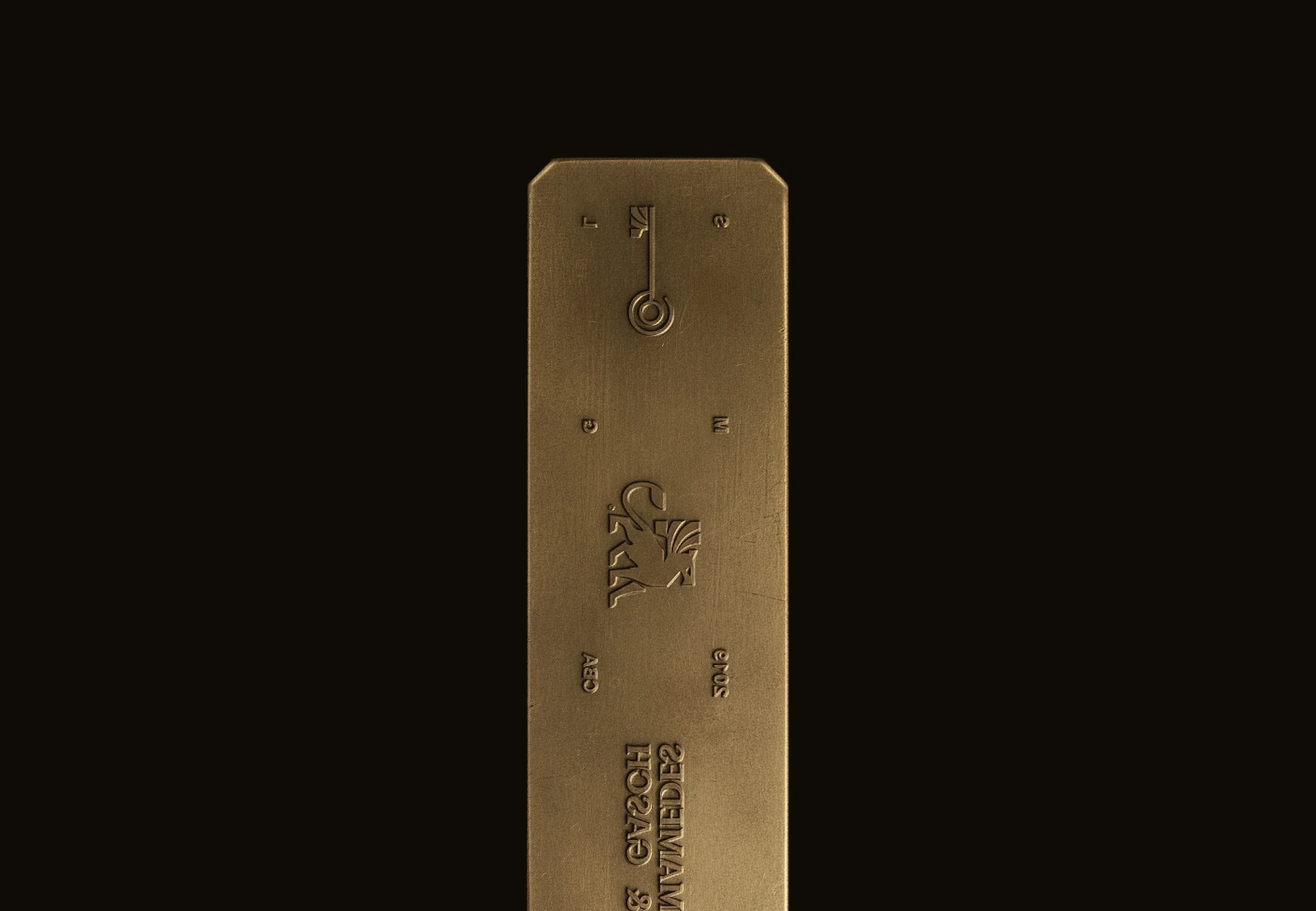 Close-up studio shot of a metal object, possibly a ruler or measuring tool, with engraved details, illuminated against a dark background.