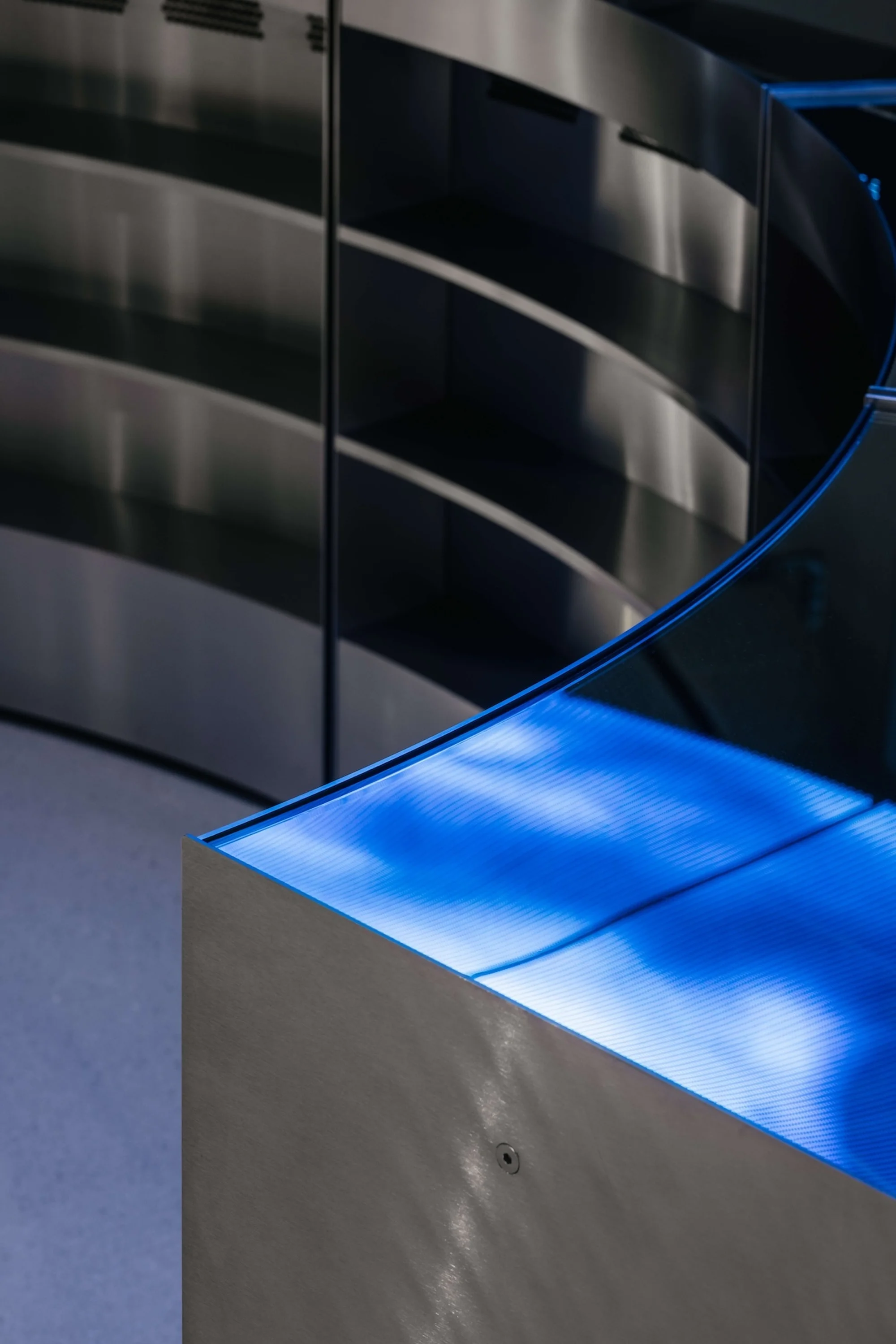 Abstract architecture with metallic surfaces and blue LED lighting creating a modern and minimalist visual composition.