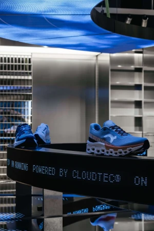 Display of On brand athletic shoes in store. Three shoes in various colors displayed on illuminated shelf. Interior product shot.