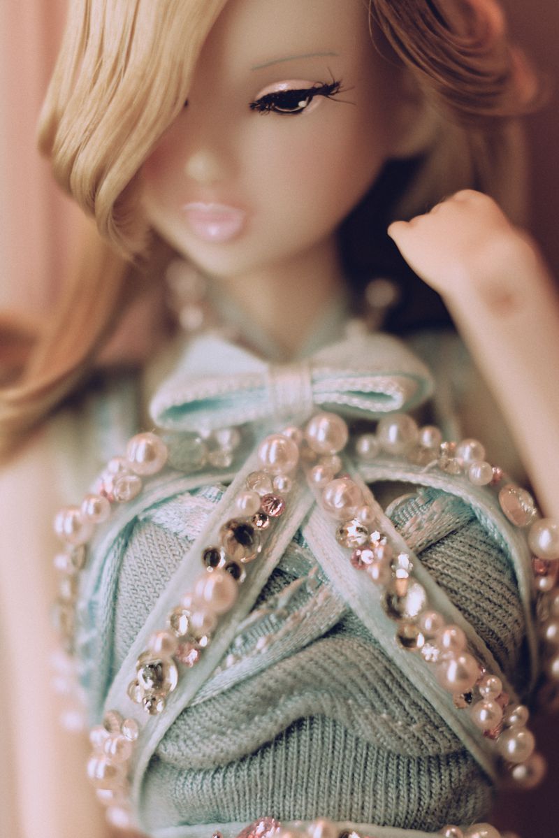 Fashion doll portrait. Detailed blue dress adorned with faux pearls and crystals. Fair skin, blonde hair, striking eye makeup.