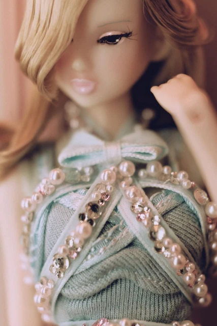 Fashion doll portrait. Detailed blue dress adorned with faux pearls and crystals. Fair skin, blonde hair, striking eye makeup.