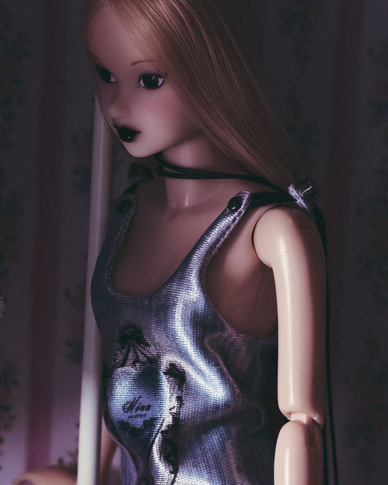 Close-up of fashion doll with blonde hair wearing a metallic dress, showcasing beauty and style in an indoor setting with patterned backdrop.