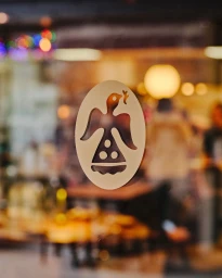 An oval decal of an angel bird holding a branch on a glass window with a blurred interior background.