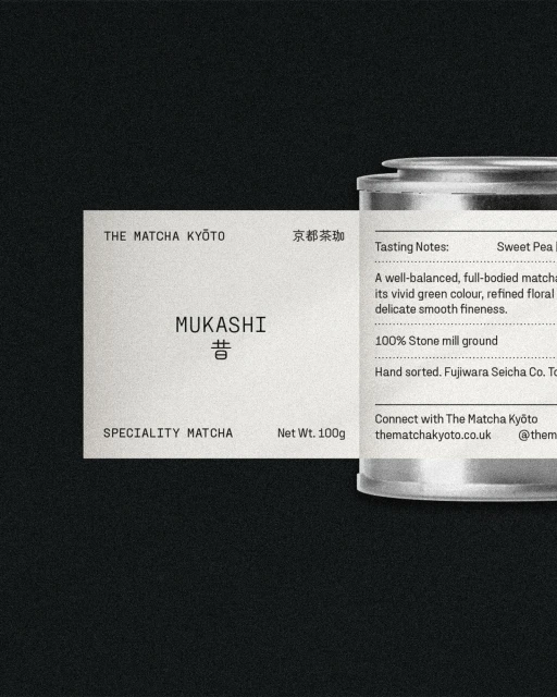 The Matcha Kyoto's Mukashi matcha product with its packaging featuring a label and a silver tin container, presented on a dark backdrop.