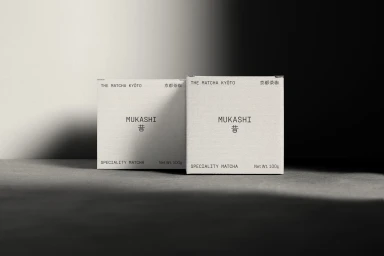 Two minimalist off-white matcha tea packaging boxes for The Matcha Kyoto set under dramatic directional studio lighting.