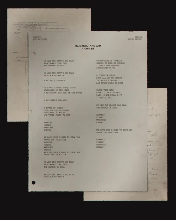 Sheets of printed lyrics for 'Me, Myself, and Sam Track #2', in a photo studio setting, featuring song lyrics and handwritten notes.
