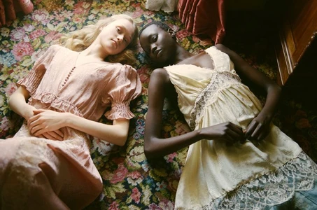 Two female models lying side by side on a patterned floral carpet in pastel dresses for Sea SS 26 editorial