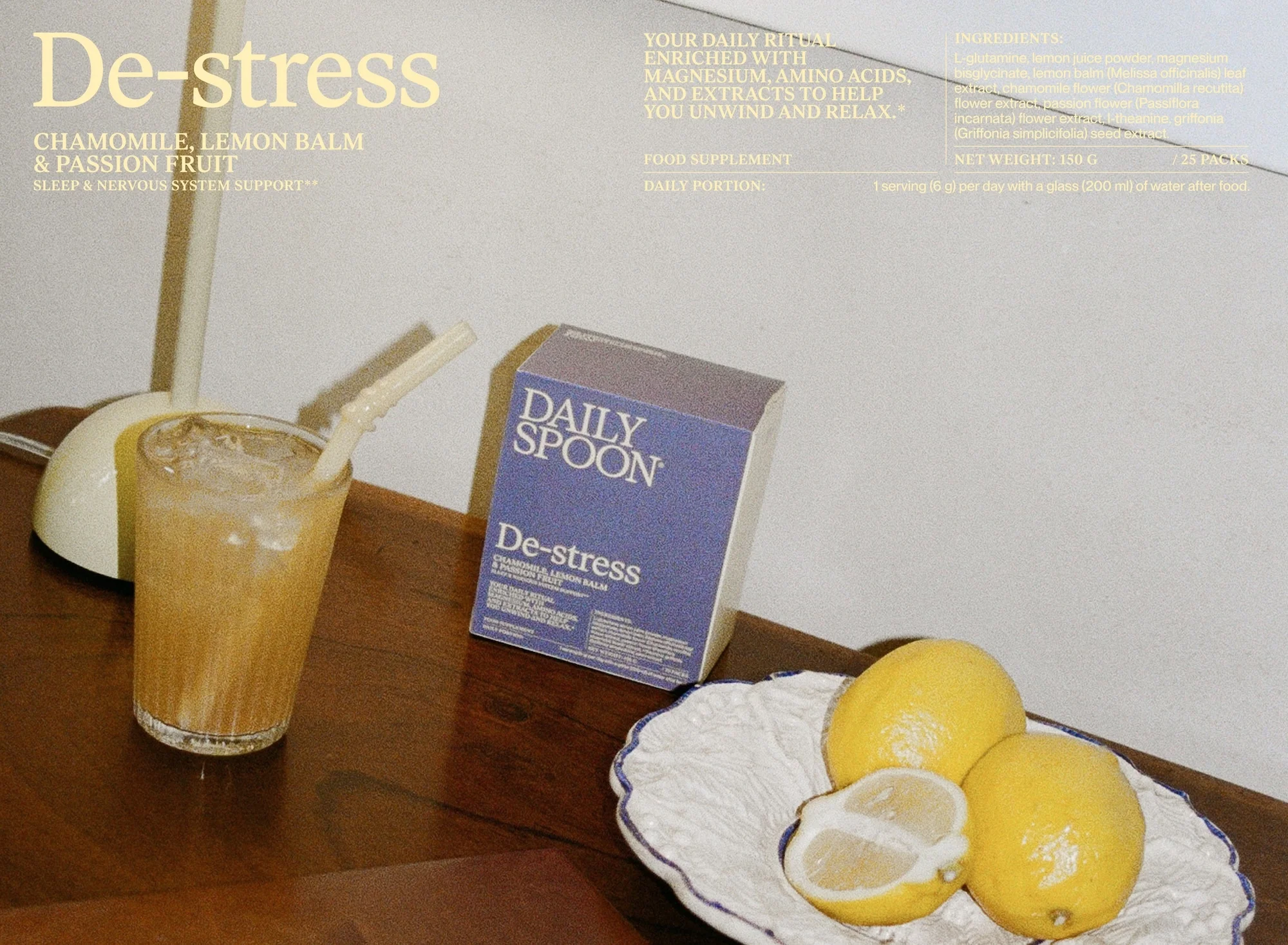 Close-up product shot of Daily Spoon De-stress supplement box, glass with straw, lemons on a wooden table, well-lit and inviting.