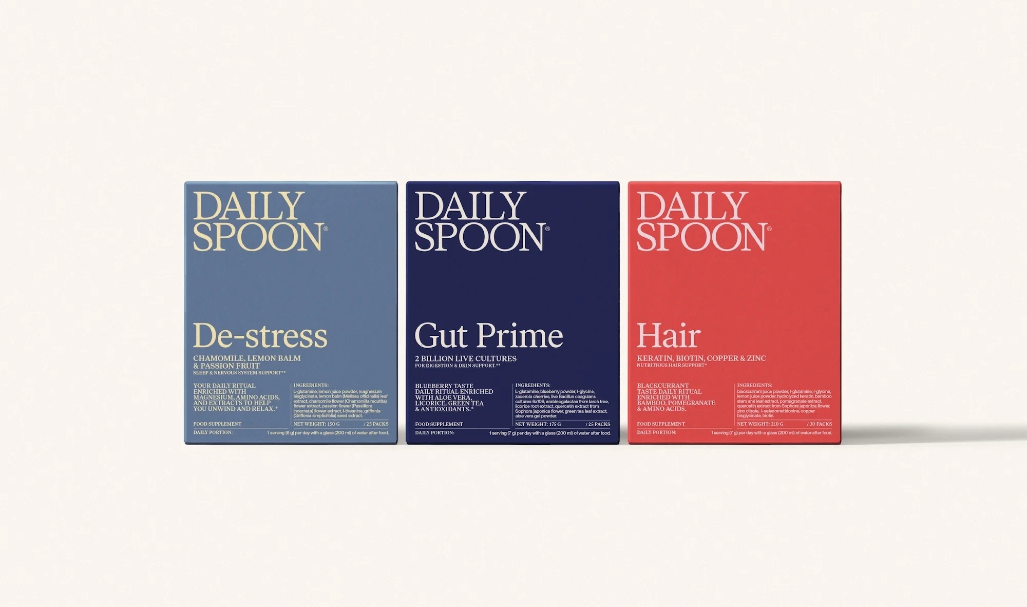Three Daily Spoon supplement boxes in blue, navy, and red. The boxes represent De-stress, Gut Prime, and Hair supplements.