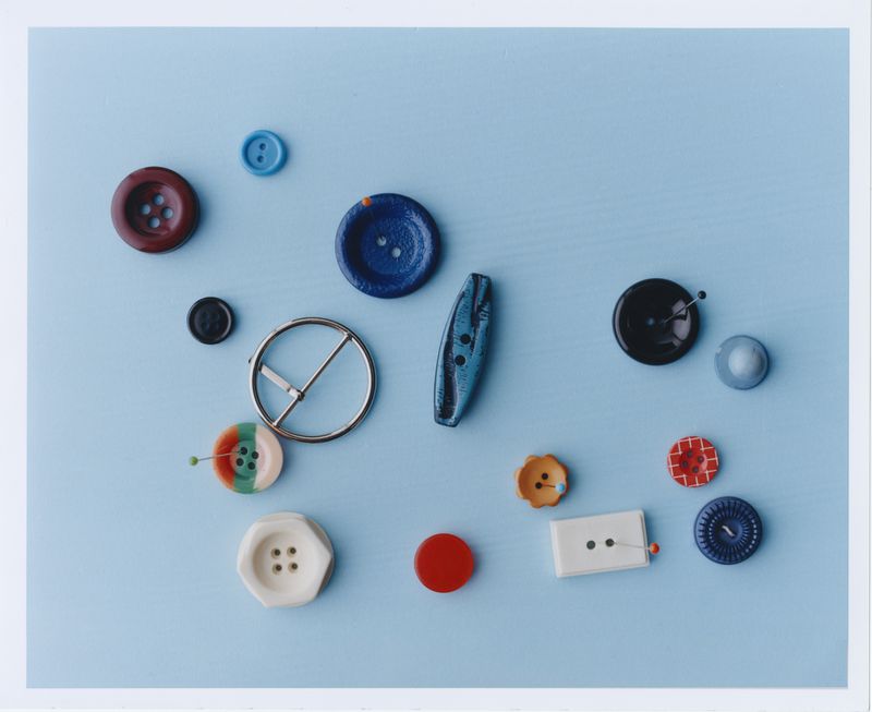 Assorted colorful buttons and metal buckle on a light blue background, flat lay design for sewing, crafting, and textile design.