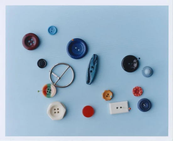 Assorted colorful buttons and metal buckle on a light blue background, flat lay design for sewing, crafting, and textile design.