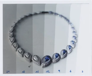Diamond and sapphire necklace arranged in a curve across vertical grey scale gradation bands