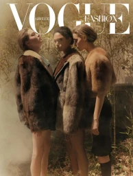 Three female models wearing textured fur jackets posing outdoors amidst hazy foliage for Vogue Greece.