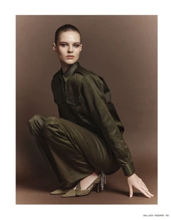 Model in olive green shirt and trousers crouching against a brown studio backdrop for Madame Germany Safari Couture.