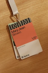 VIP event pass badge for Mary Jean Brown with Aptos branding hanging on a light wood grain surface