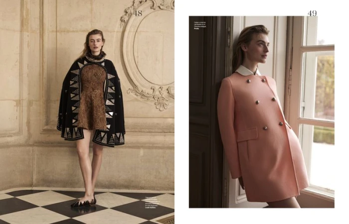 Fashion editorial shot featuring a woman in a cape next to a woman in a coat by a window, showcasing apparel and indoor settings.