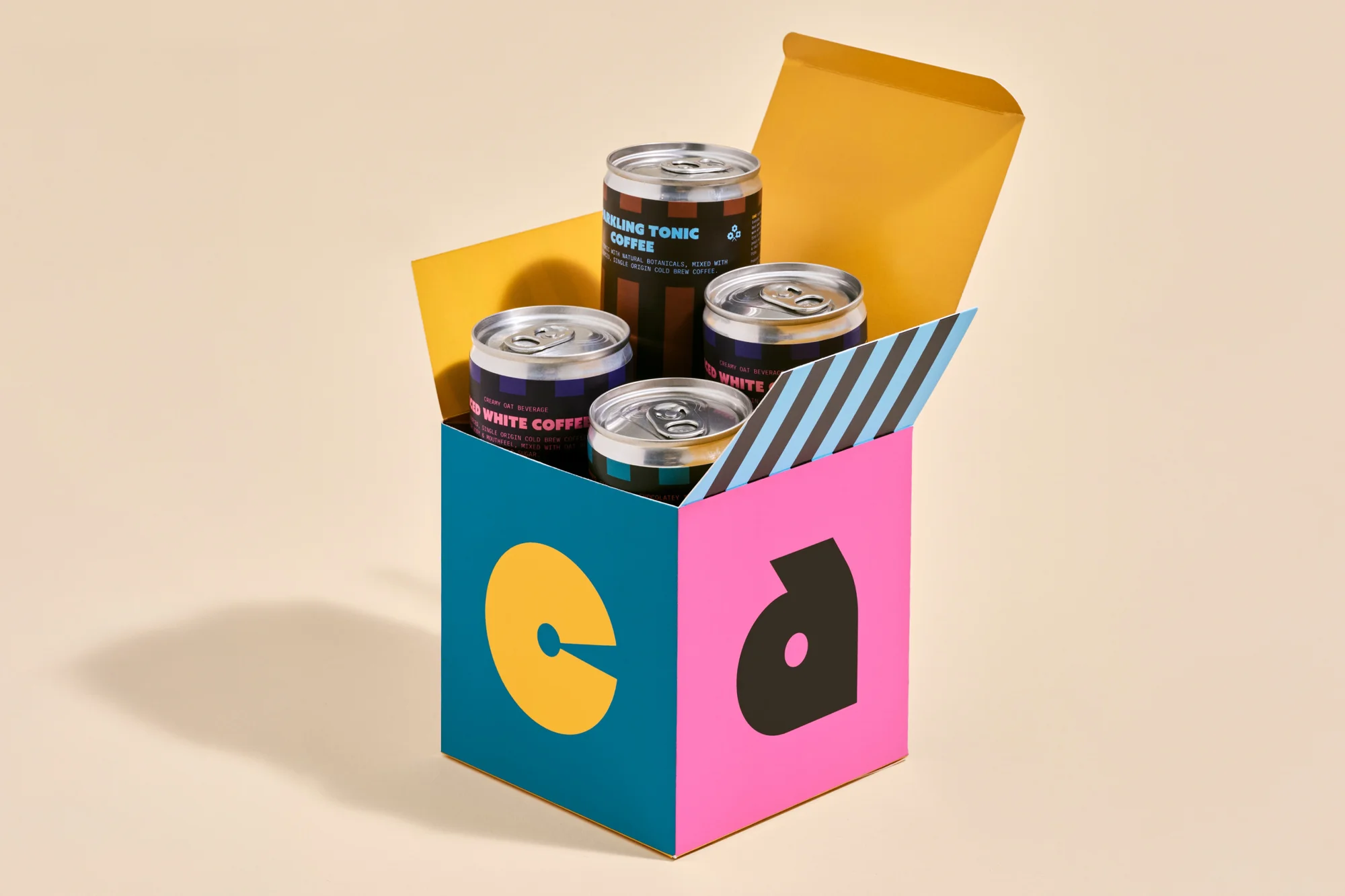 Four canned coffee drinks in a colorful branded box with yellow and blue panels, all set against a neutral background.