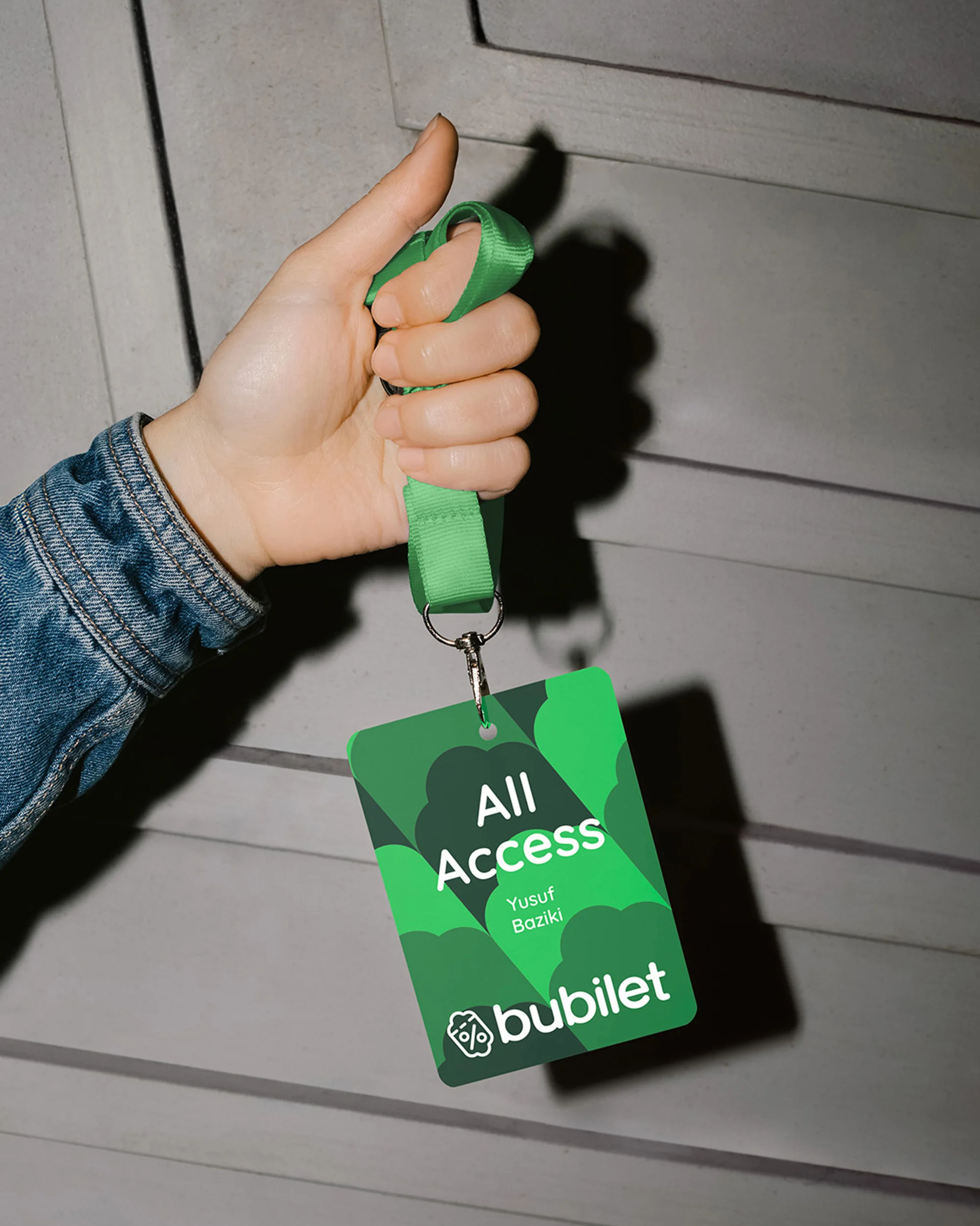 Close-up of a hand holding a green employee badge with the bubilet logo and 'All Access' text, suspended from a green lanyard.