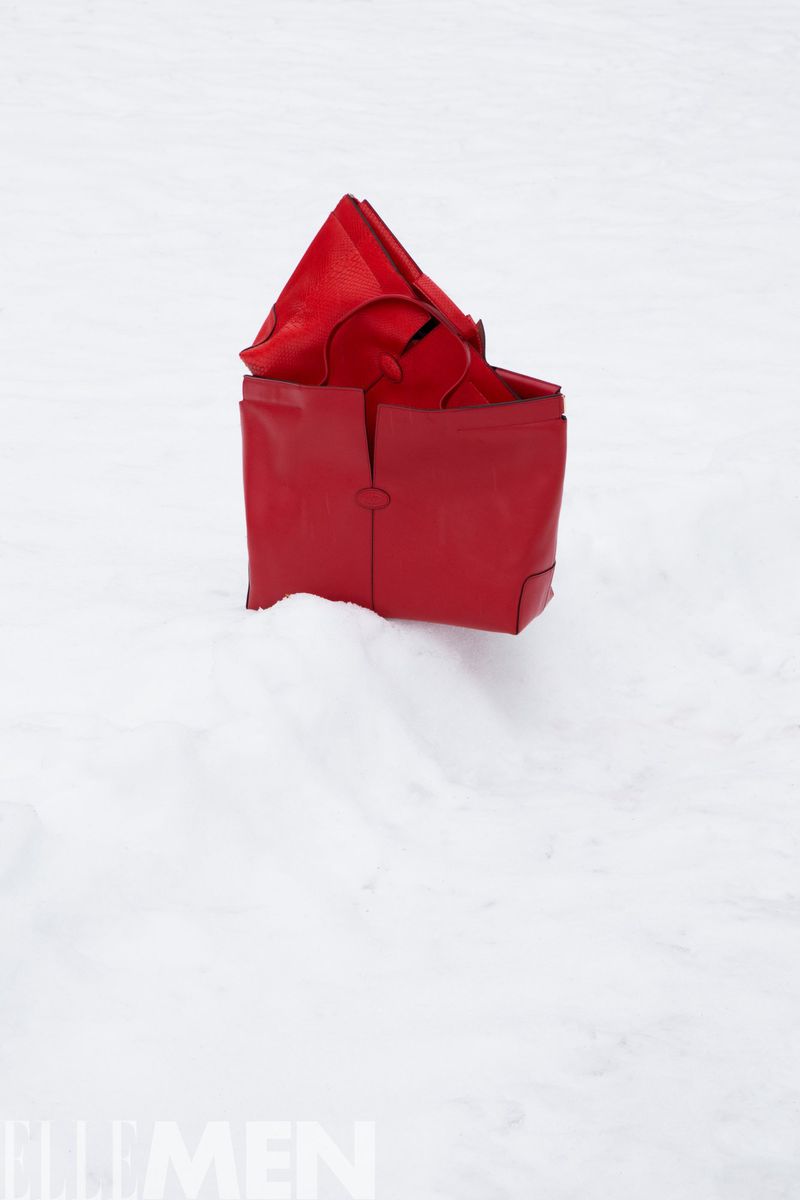 Striking fashion shot of a red leather tote bag in pristine snow, showcasing winter style and minimalist composition in outdoor setting.