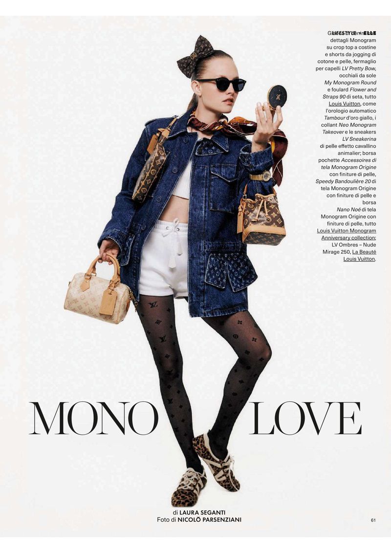 Fashion editorial shot of a female model wearing a denim jacket, white shorts and logo printed tights, posing against a white background.