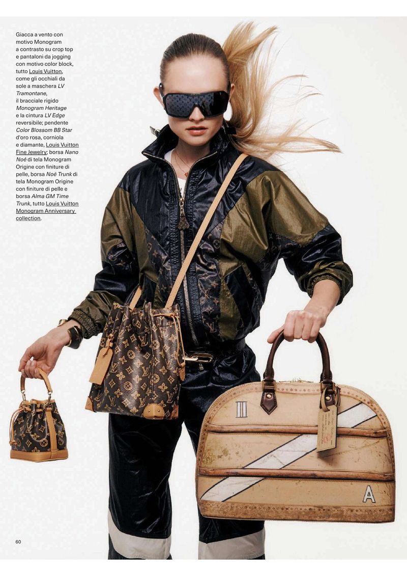 A woman poses with Louis Vuitton handbags, wearing a track suit and sunglasses with a Monogram pattern on a white studio backdrop.