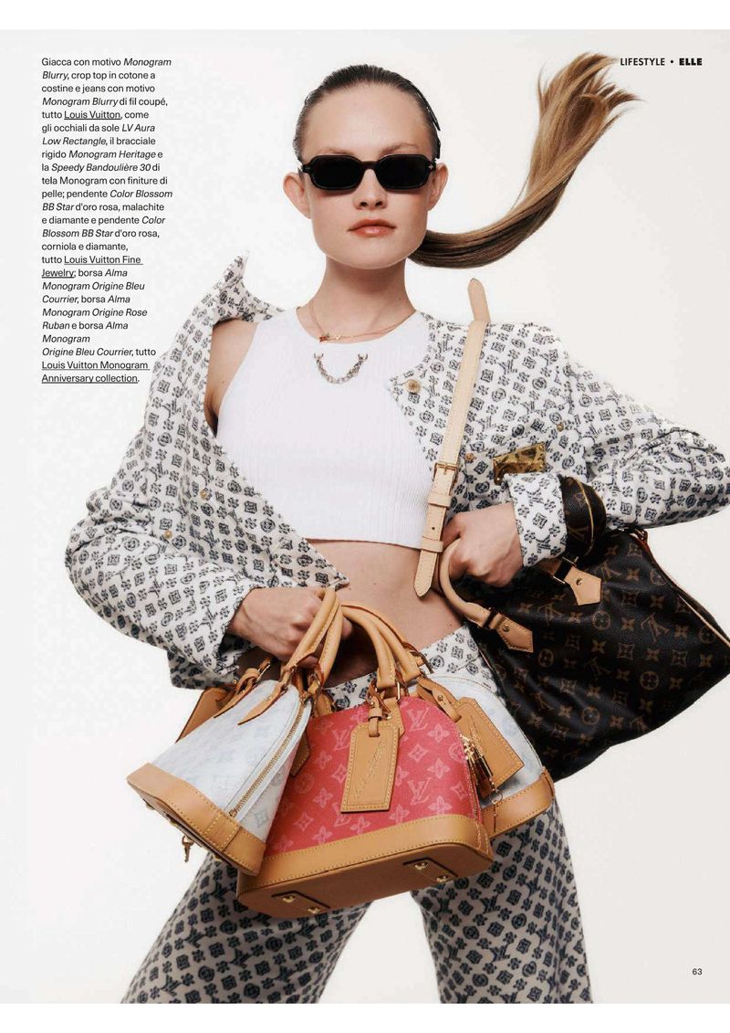 Fashionable woman posing outdoors in a patterned suit, white top, sunglasses, and jewelry, holding three Louis Vuitton handbags.