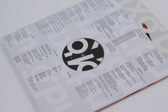 Close-up of a vinyl record cover with song lyrics and a minimalist design, featuring bold typography and a clean, modern aesthetic.