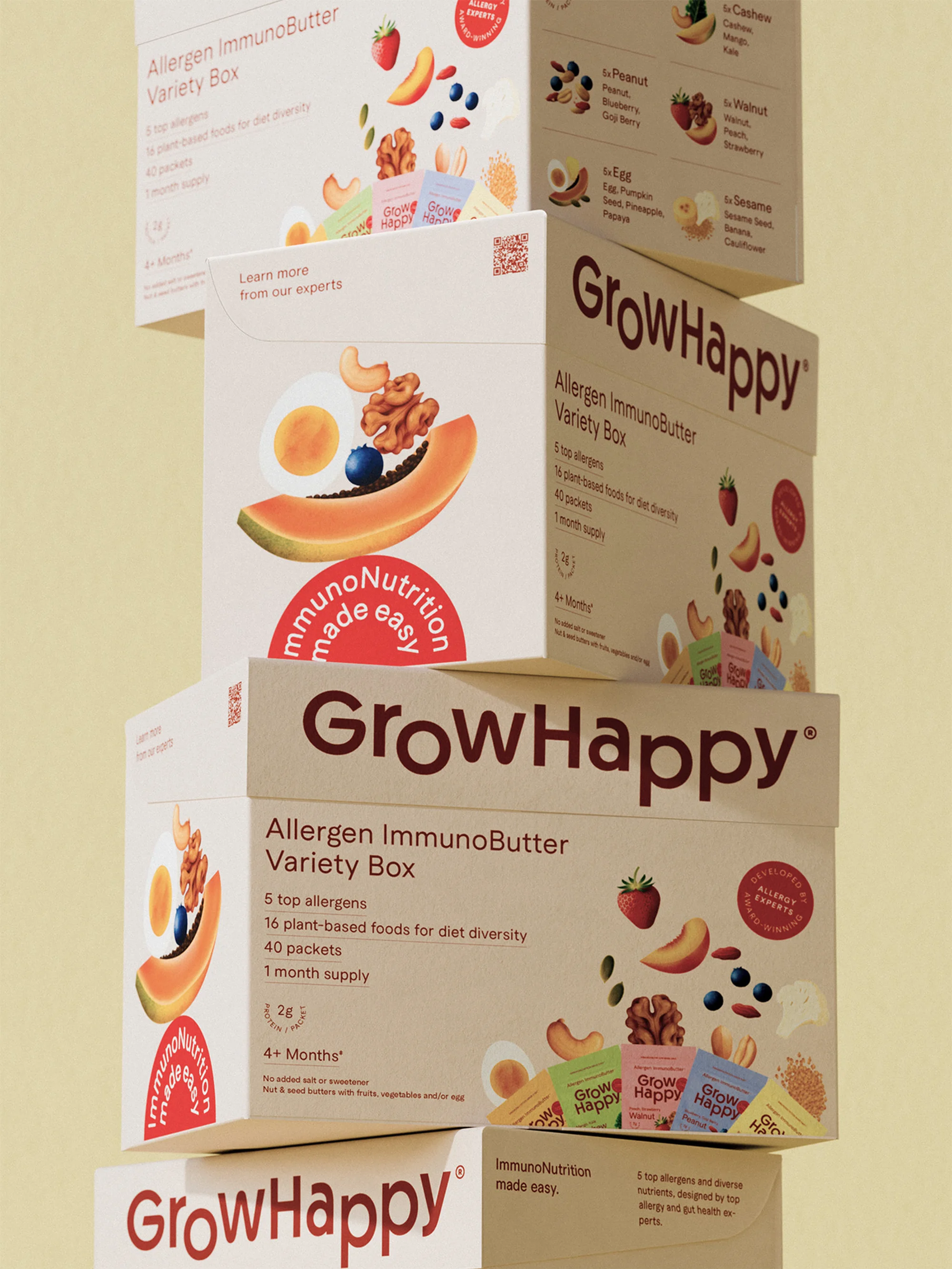Stack of GrowHappy Allergen ImmunoButter Variety Boxes on a light yellow background, showcasing food product packaging and design.