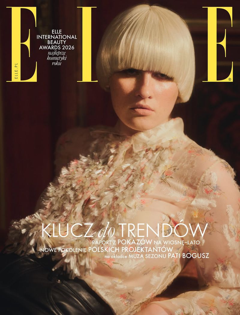 Elle magazine cover featuring a blonde woman with a blunt bob, wearing a sheer floral top, against a dark red background.