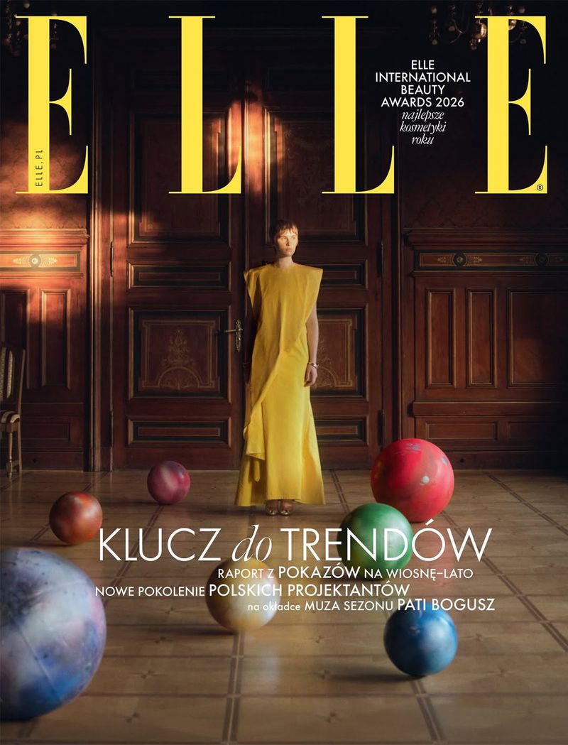 Elle magazine cover featuring a woman in a yellow dress, standing in front of dark wooden doors, surrounded by colorful spherical props.