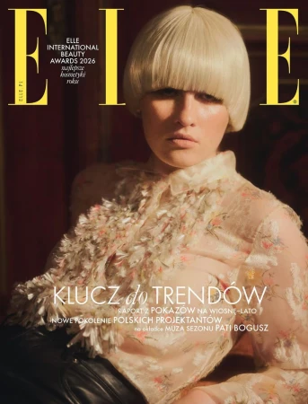 Model with a blonde bob wig wearing a sheer patterned blouse and dark trousers for Elle Poland cover.