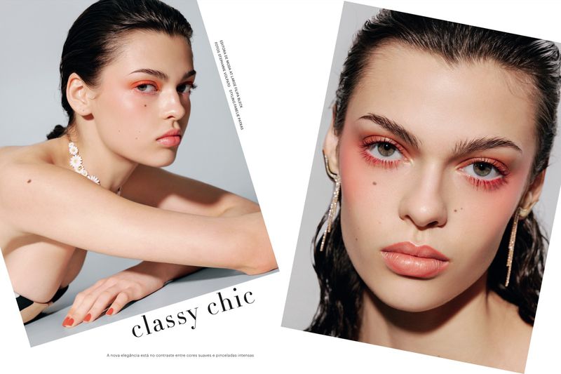 Fashion editorial featuring a young woman with a clean beauty look, coral eye makeup, visible jewelry, and sleek, dark hair against a grey background.