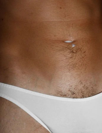 Close-up shot of a person's midsection with tan skin, a navel with a white substance, and white underwear visible at the lower abdomen.