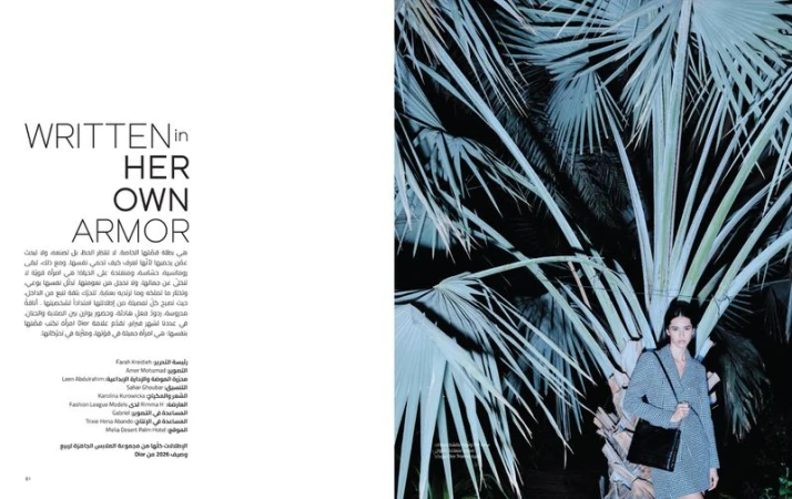 Fashion editorial shot: A young woman with a black purse stands by a large palm tree in a night scene with cool, cinematic lighting.