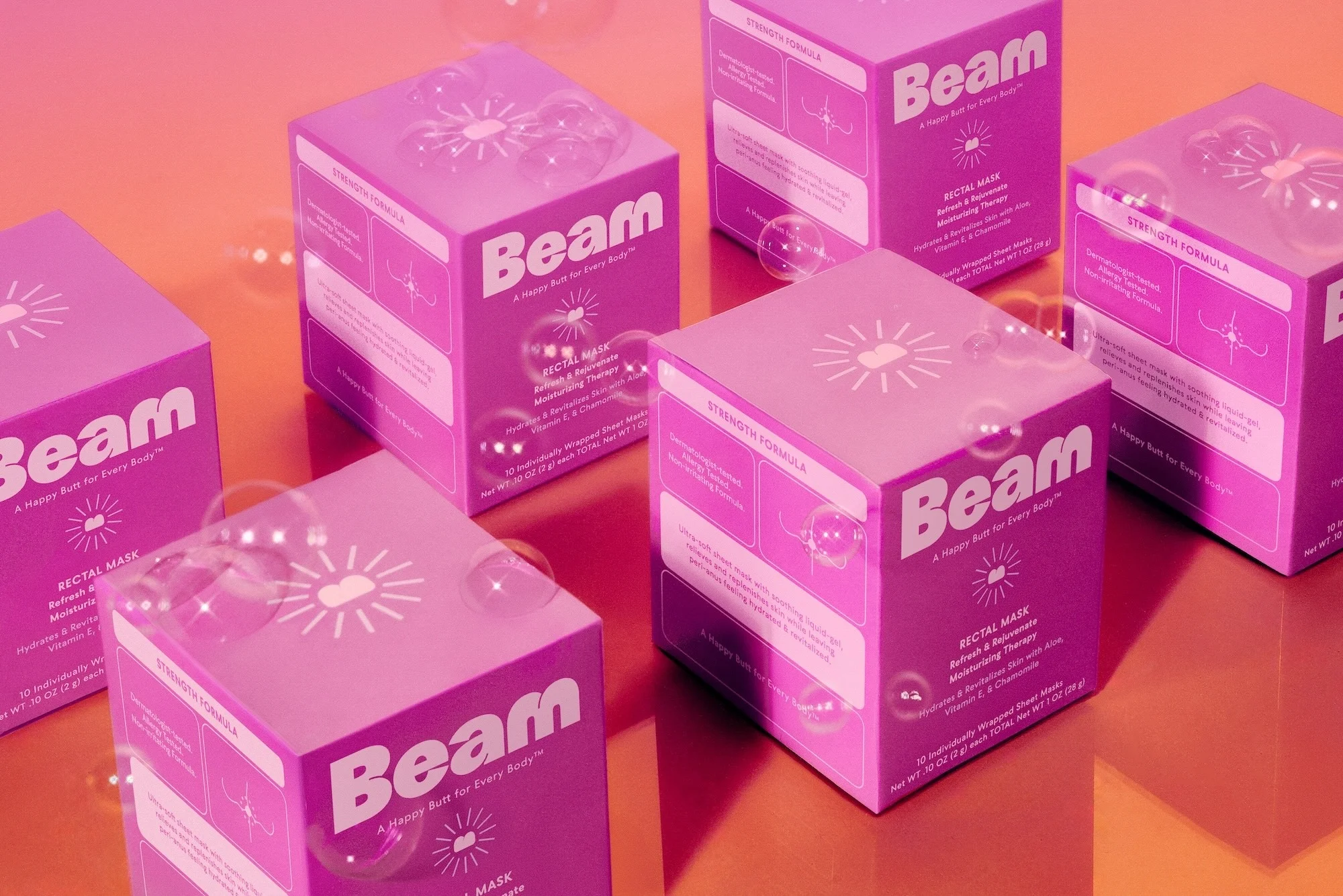 Several pink boxes of Beam brand rectal masks are arranged on a reflective orange surface, with translucent bubbles floating nearby.