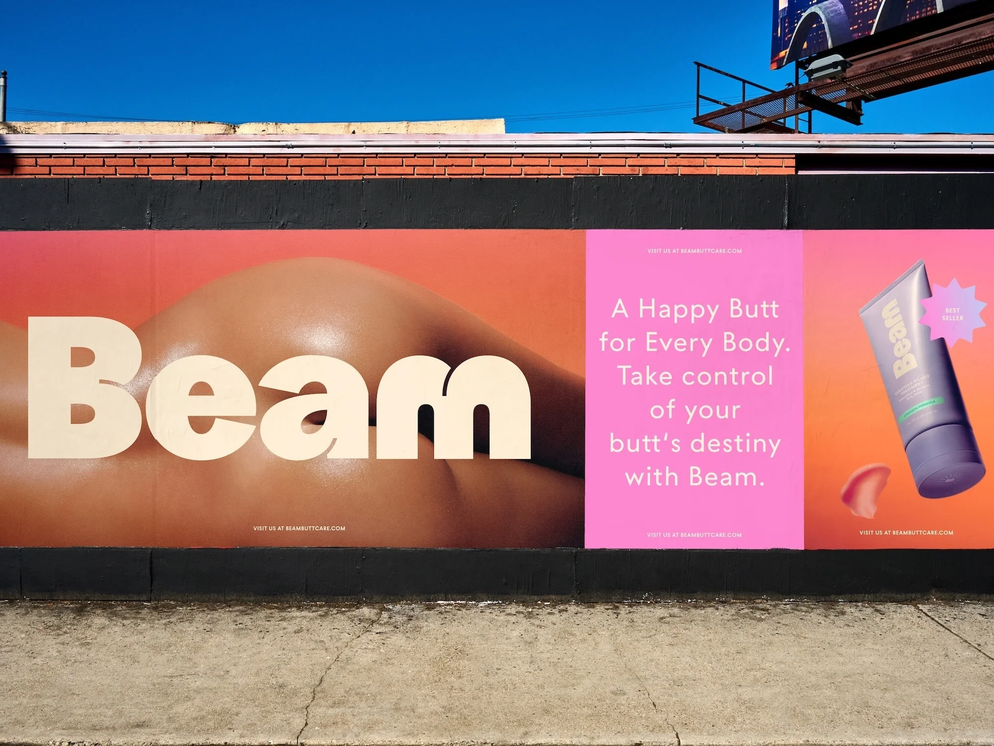 A large billboard features an ad for Beam skincare with a close-up of a butt, cream tube, set against an urban brick wall background.