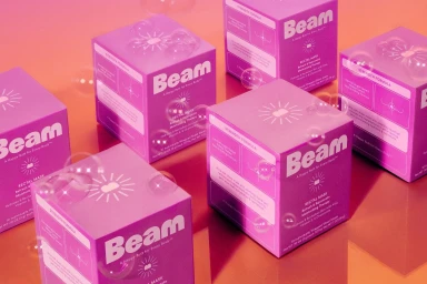 Multiple square purple product boxes branded Beam arranged neatly with floating transparent soap bubbles on a glossy surface.