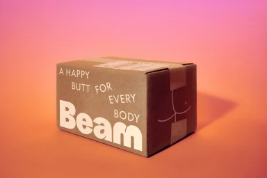 Brown cardboard shipping box with white printed text reading Beam against a warm pink and orange gradient background.