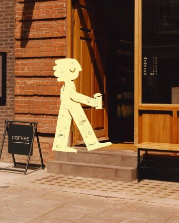 Street-level view of a cartoon figure entering a coffee shop, featuring a brown brick wall and a black A-frame 'Coffee' sign.