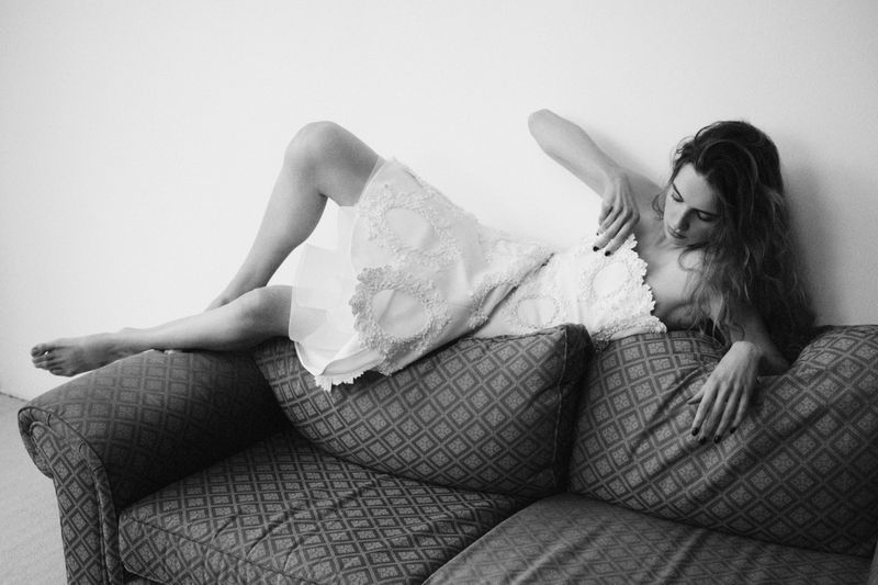 Monochrome portrait of model Lota Blaskovic reclining on a patterned couch wearing a white dress for Financial Times HTSI Magazine