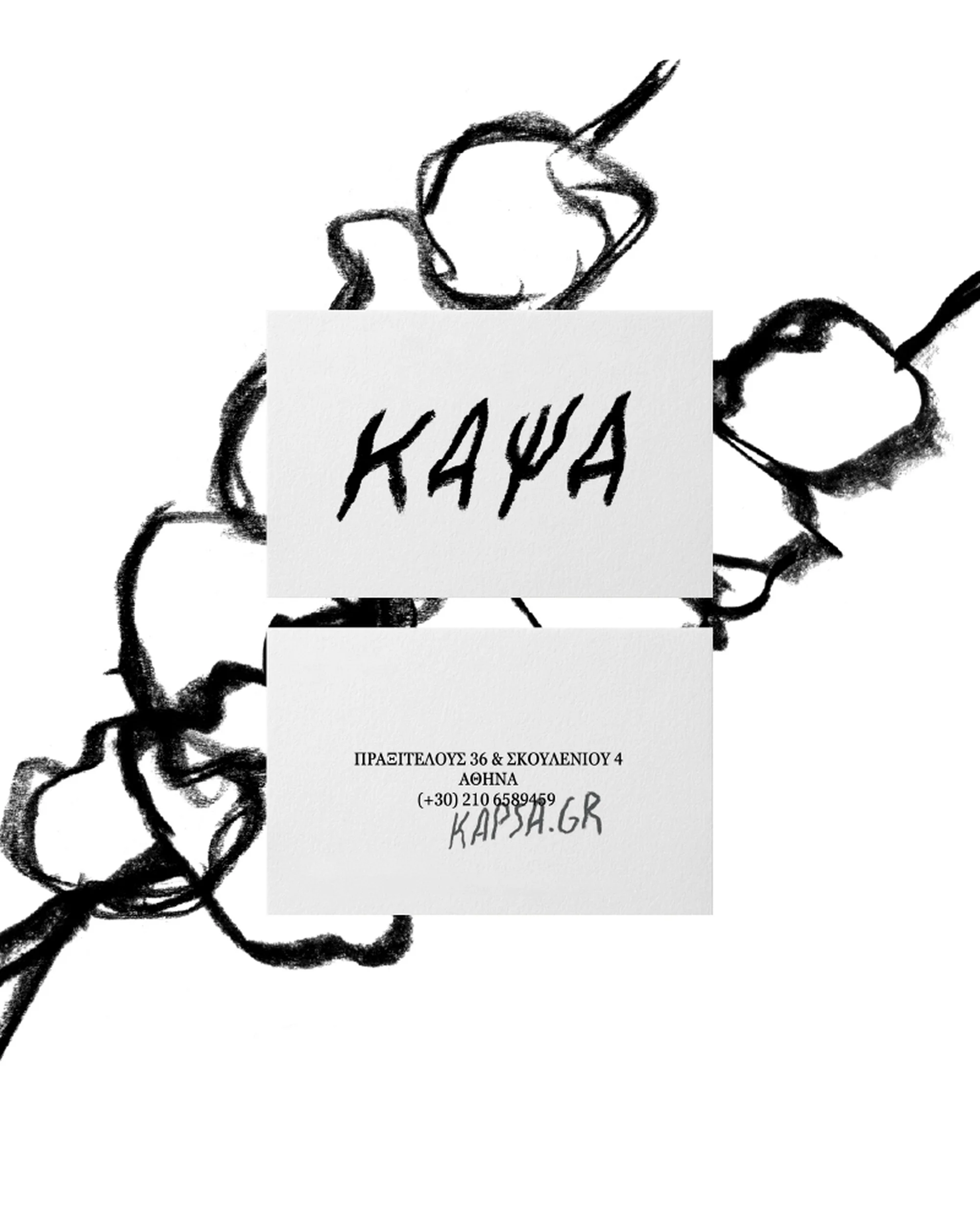 Close-up product shot of two white business cards with black calligraphic font over black abstract drawing on a white backdrop.