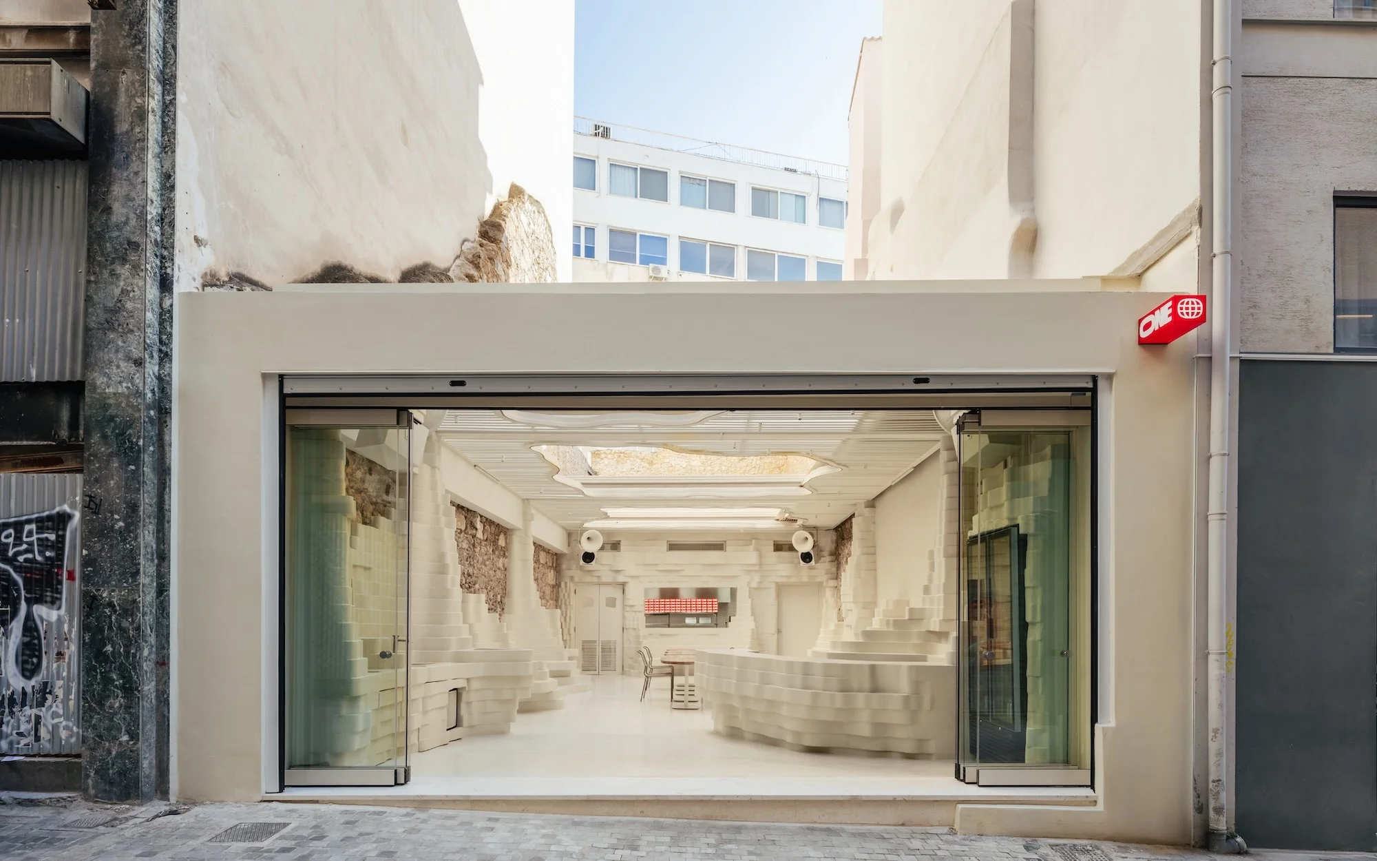 Minimalist interior design of a store with white walls and modern display structures, showcasing clean lines and open space, urban setting.