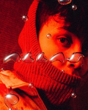 Close-up portrait of a person in a hooded garment with water droplets, set against a red backdrop, creating a surreal and unique visual effect.
