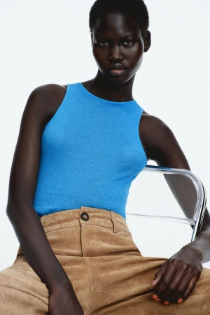 Model Chudier Billy wearing a blue sleeveless top and tan suede trousers against a white seamless background for Zara February 2026