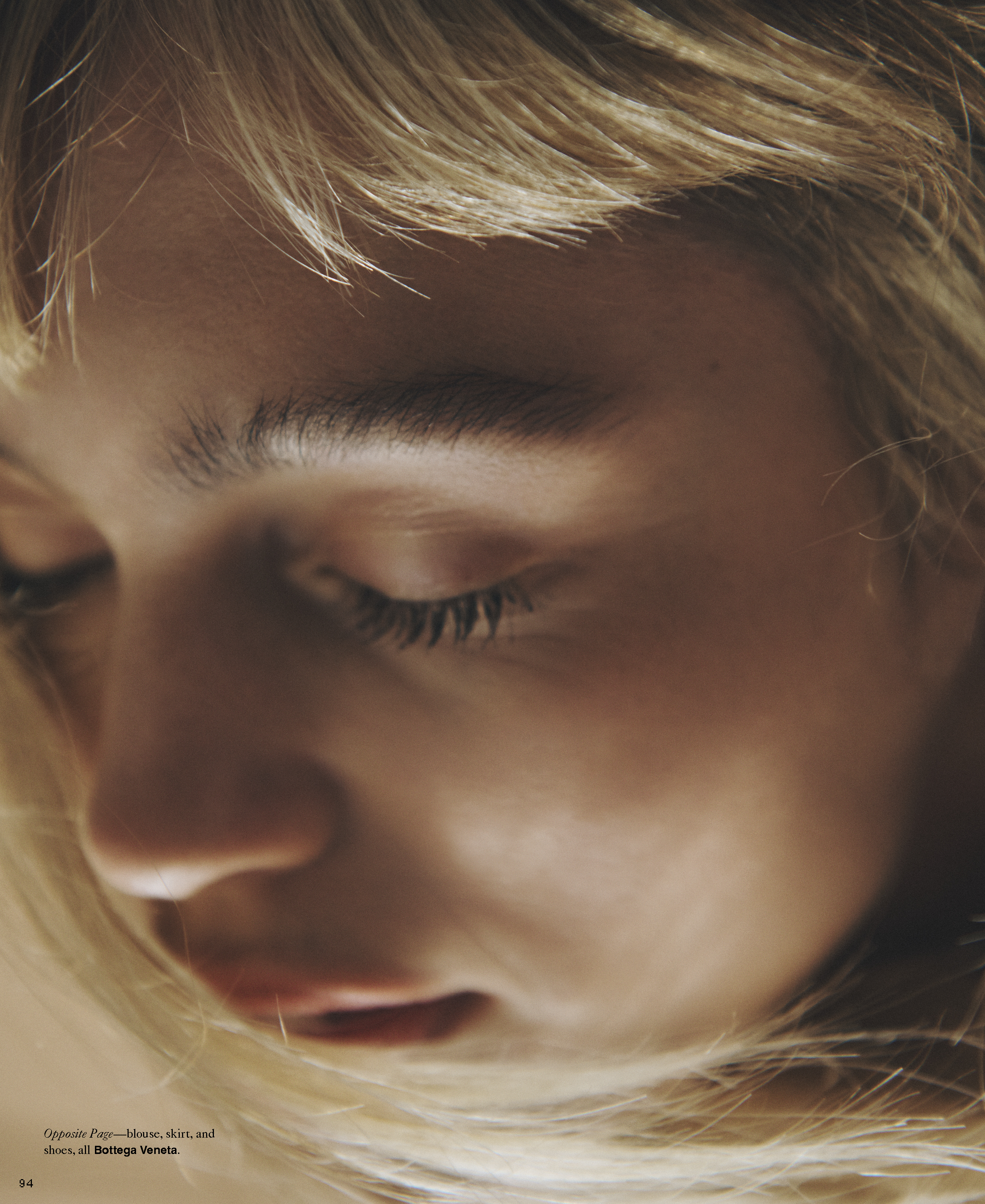 Close-up portrait of a woman with blonde hair and closed eyes in soft, warm lighting, showcasing her facial features and hair texture.