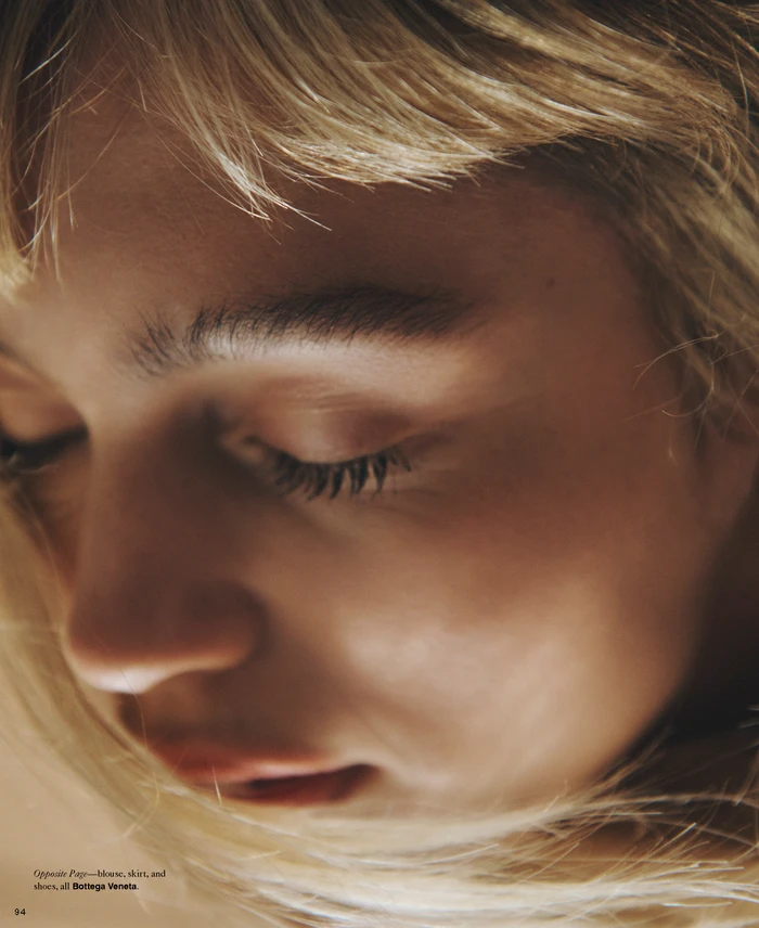 Close-up portrait of a woman with blonde hair and closed eyes in soft warm lighting